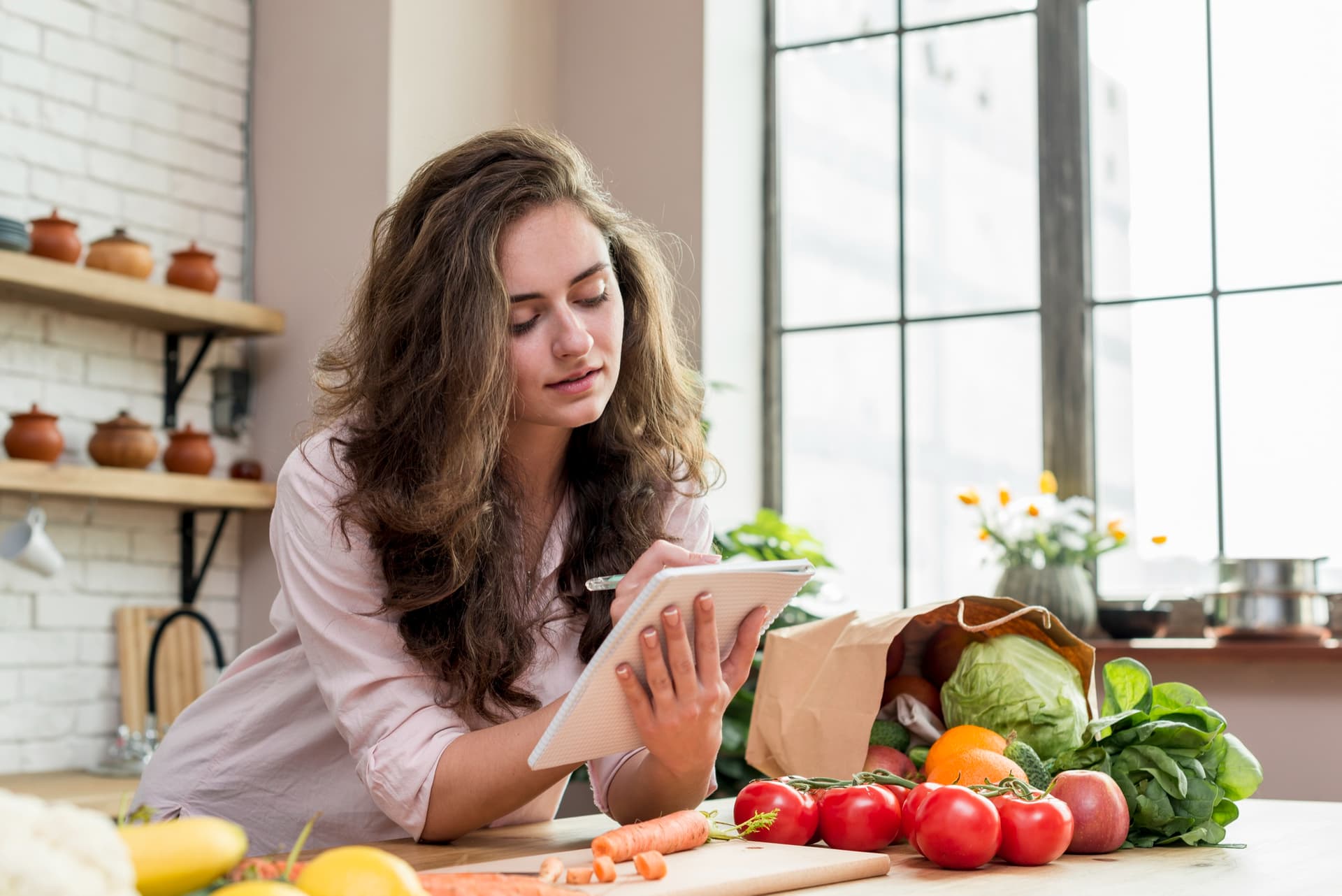 Mulher preparando refeição saudável enquanto organiza plano de dieta para emagrecer